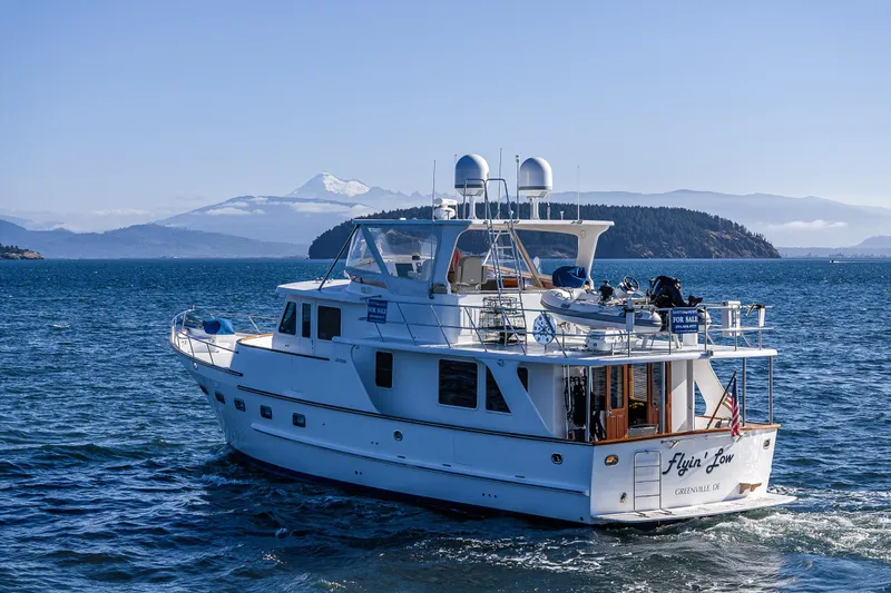 Flyin Low Yacht Photos Pics 2007 DeFever 56 yacht cruising on scenic blue waters with mountainous backdrop.