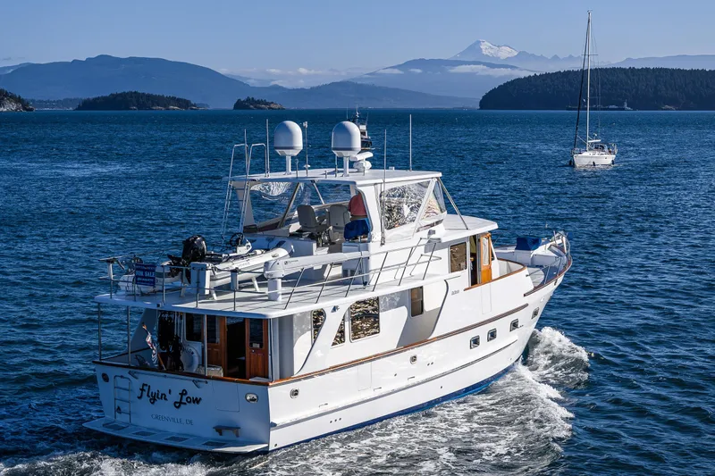 Flyin Low Yacht Photos Pics 2007 DeFever 56 yacht cruising in scenic waters with mountains in the background.