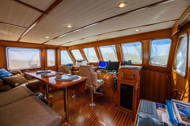 Flyin Low Yacht Photos Pics Luxurious 2007 DeFever 56 yacht interior with wood paneling, navigation equipment, and comfortable seating.