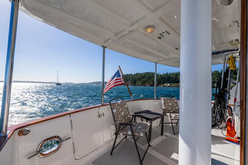 Flyin Low Yacht Photos Pics DeFever 56 yacht deck, 2007 model, with chairs and American flag, overlooking scenic ocean view.