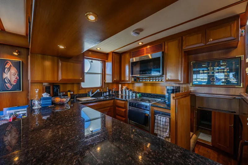 Flyin Low Yacht Photos Pics Luxurious 2007 DeFever 56 yacht kitchen with wooden cabinetry and modern appliances.