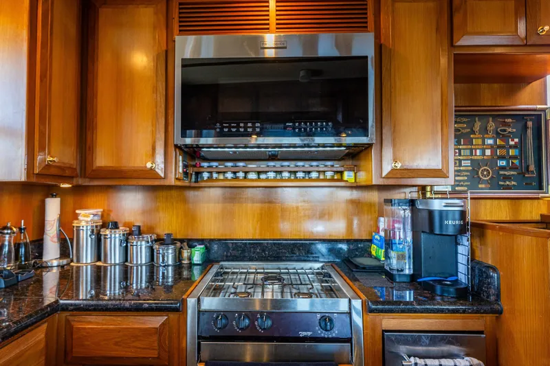 Flyin Low Yacht Photos Pics Luxurious 2007 DeFever 56 yacht kitchen with wooden cabinets and modern appliances.