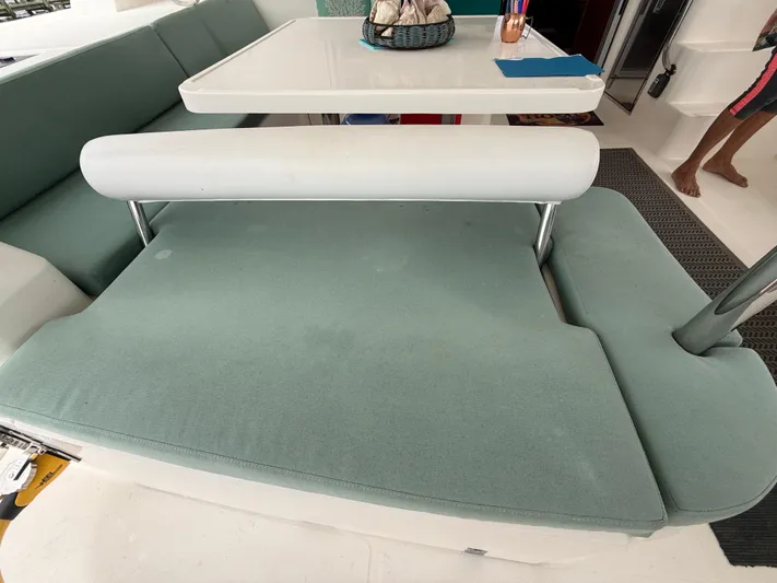 White Wings Yacht Photos Pics Interior seating area on a 2013 Leopard 48 yacht with teal cushions and a white table.