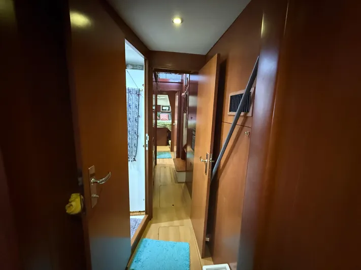 White Wings Yacht Photos Pics Interior hallway of 2013 Leopard 48 yacht with wooden paneling and blue rugs.