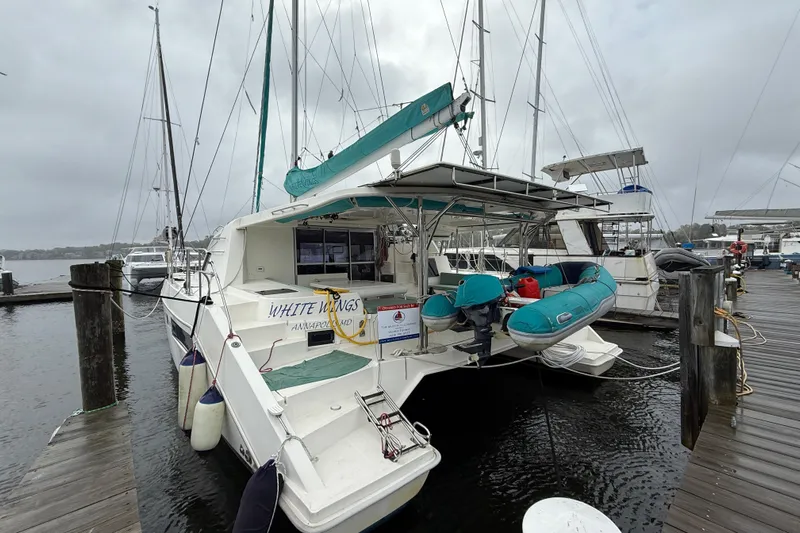 White Wings Yacht Photos Pics 2013 Leopard 48 catamaran docked, featuring a turquoise dinghy and overcast sky.