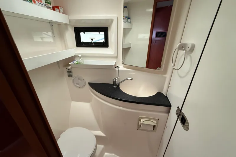 White Wings Yacht Photos Pics Compact bathroom in a 2013 Leopard 48 yacht, featuring sink, toilet, and storage shelves.