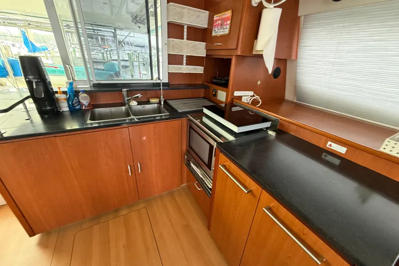 White Wings Yacht Photos Pics Modern kitchen in a 2013 Leopard 48 yacht with wood cabinetry and black countertops.