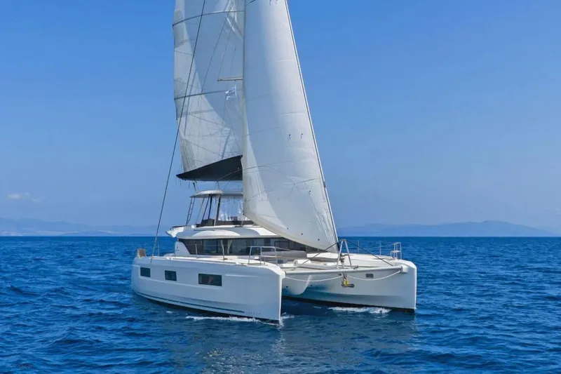  Yacht Photos Pics Sailing catamaran Lagoon 46, 2021 model, gliding on open sea under clear blue sky.