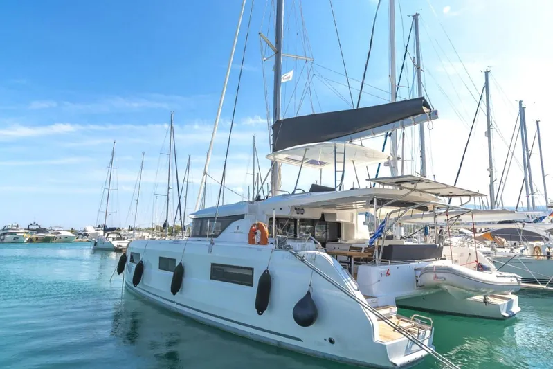  Yacht Photos Pics 2021 Lagoon 46 catamaran docked in a marina under clear blue skies.