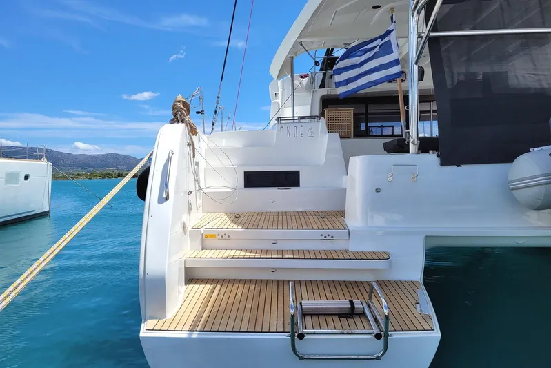  Yacht Photos Pics Lagoon 46 catamaran, 2021 model, docked with a Greek flag, wooden steps, and clear blue water.