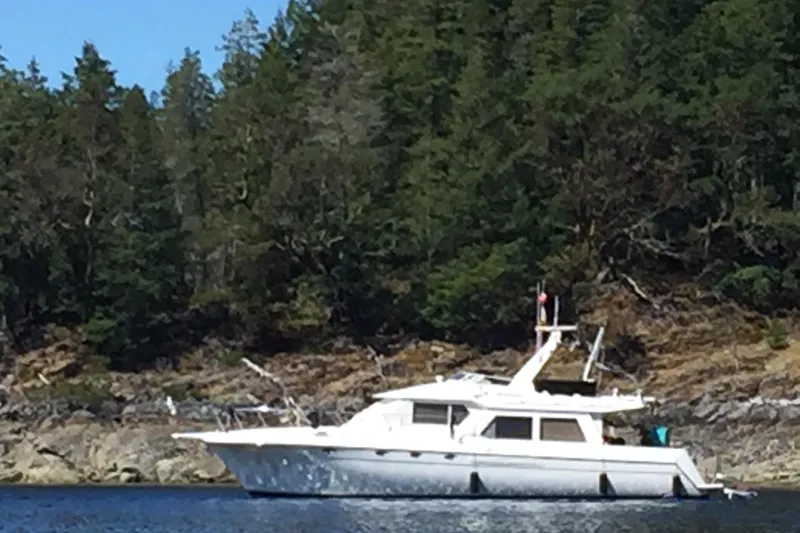 Gabbiano Yacht Photos Pics White 2000 Navigator 53 yacht anchored near a forested shoreline.