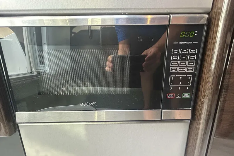  Yacht Photos Pics Modern microwave oven with digital display and control panel, reflecting a person taking a photo.