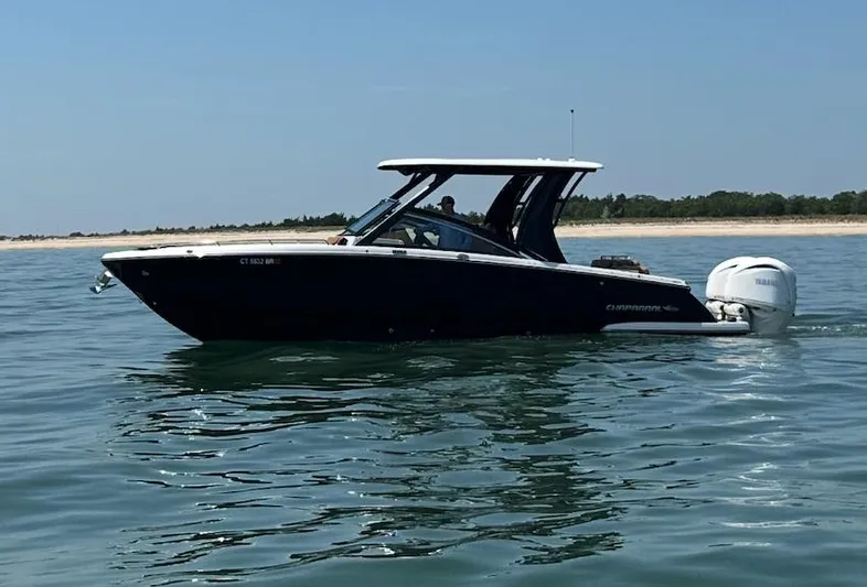  Yacht Photos Pics 2024 Chaparral 300 OSX boat cruising on calm water near a sandy shoreline.