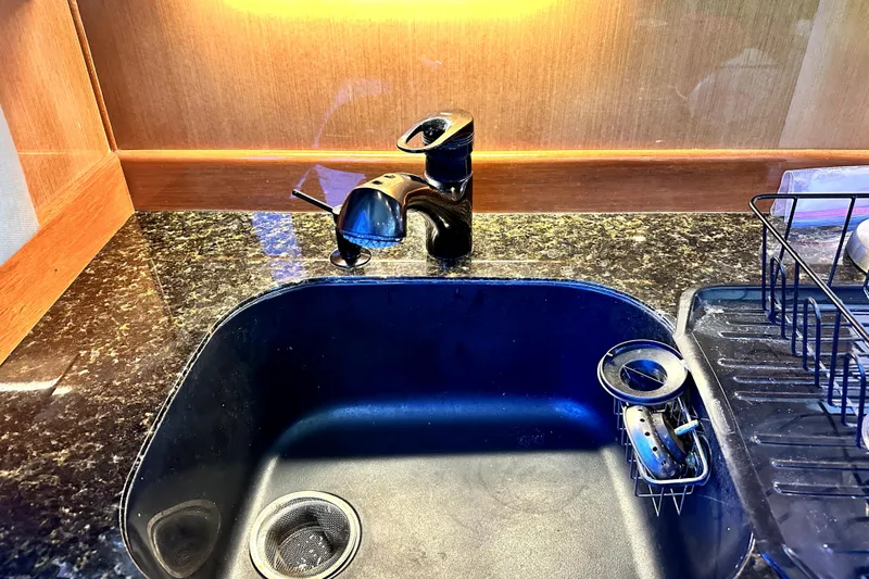 Reel Inn Yacht Photos Pics Kitchen sink with black faucet and drying rack on Viking 61 Convertible yacht, 2003 model.