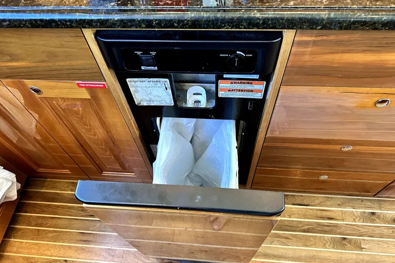 Reel Inn Yacht Photos Pics Built-in trash compactor on 2003 Viking 61 Convertible yacht with wooden cabinetry.