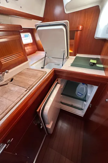 Pono Yacht Photos Pics Interior of 2006 Beneteau 423 yacht kitchen with open fridge and wooden cabinetry.