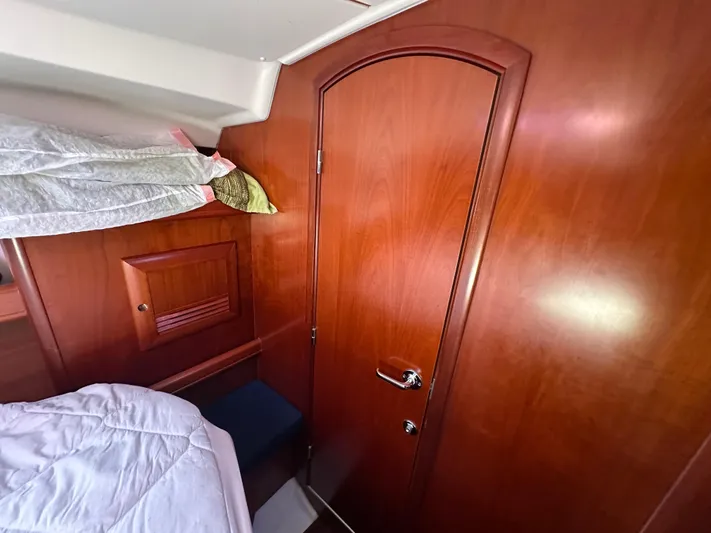 Pono Yacht Photos Pics Interior cabin of 2006 Beneteau 423 sailboat with wooden door and cozy bedding.