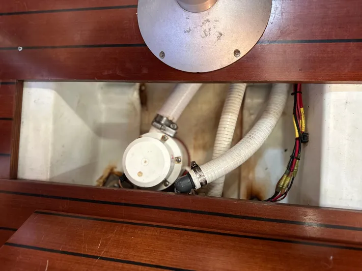 Pono Yacht Photos Pics Bilge pump system in 2006 Beneteau 423 sailboat, featuring wooden flooring and white hoses.