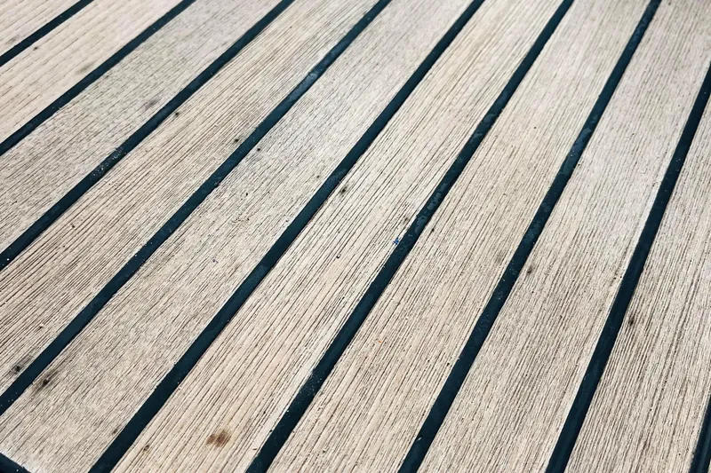  Yacht Photos Pics Teak deck of a 2006 Beneteau 473 sailboat, showcasing wood grain and black caulking.