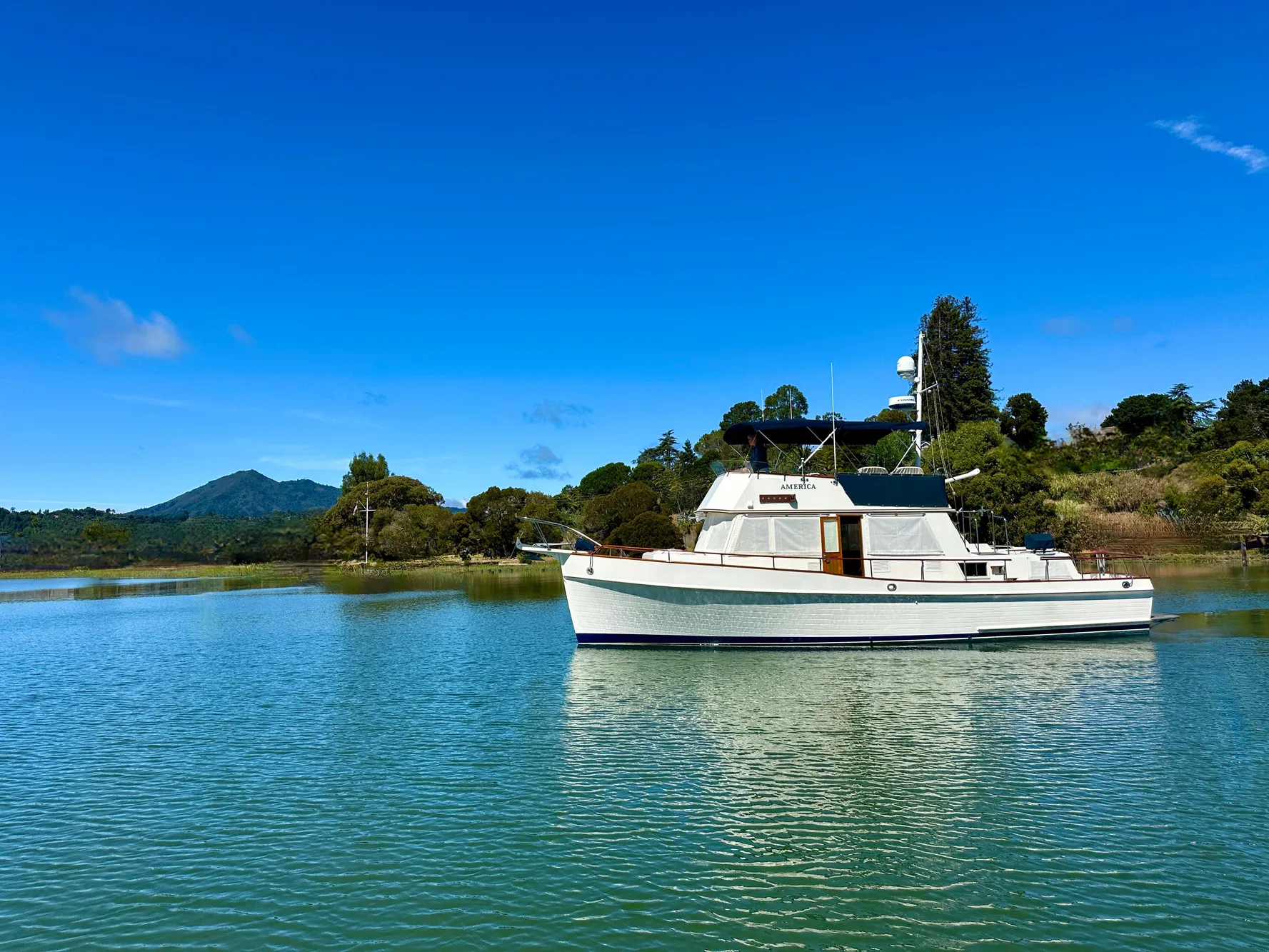 1989 Grand Banks 42 Classic yacht on serene water with lush green backdrop.