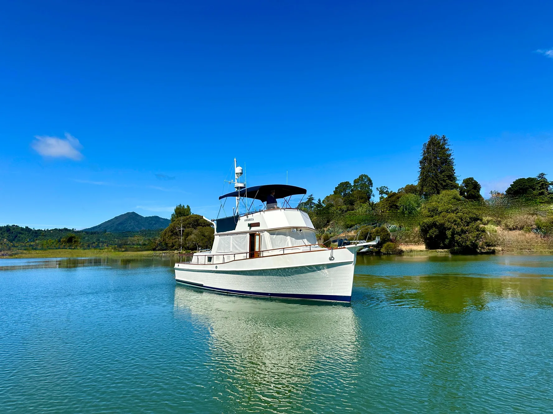1989 Grand Banks 42 Classic yacht on serene water with lush green landscape.