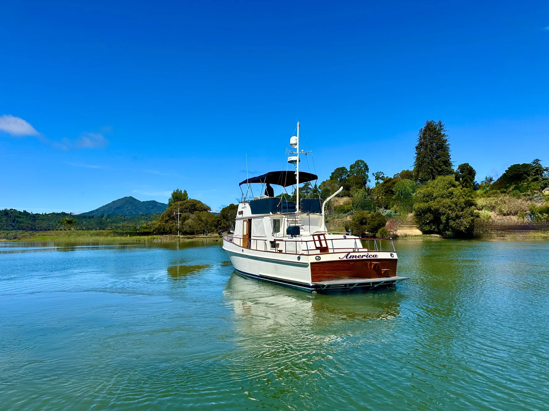 1989 Grand Banks 42 Classic yacht on serene water with lush greenery backdrop.