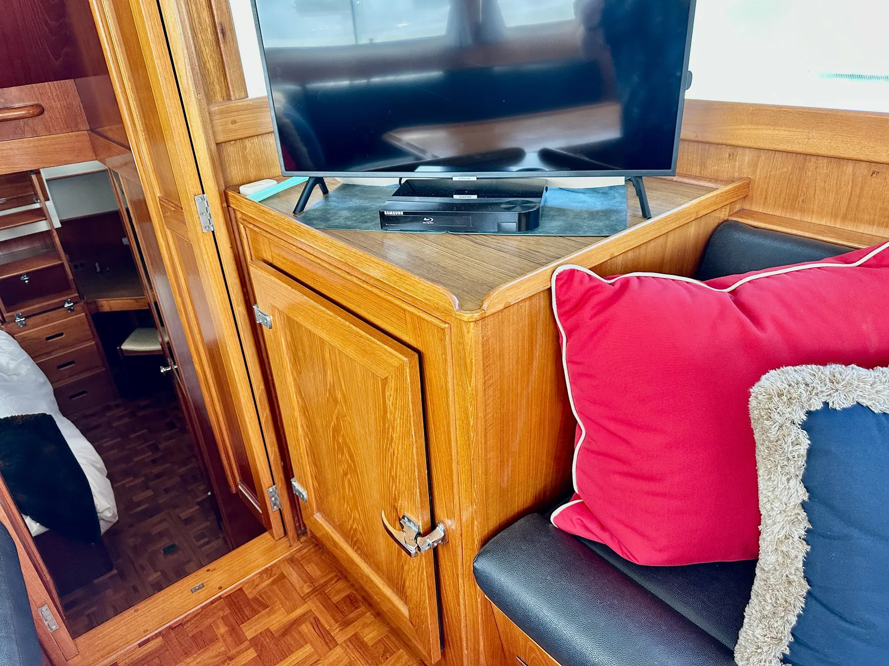 Interior of 1989 Grand Banks 42 Classic with TV, wooden cabinetry, and colorful cushions.