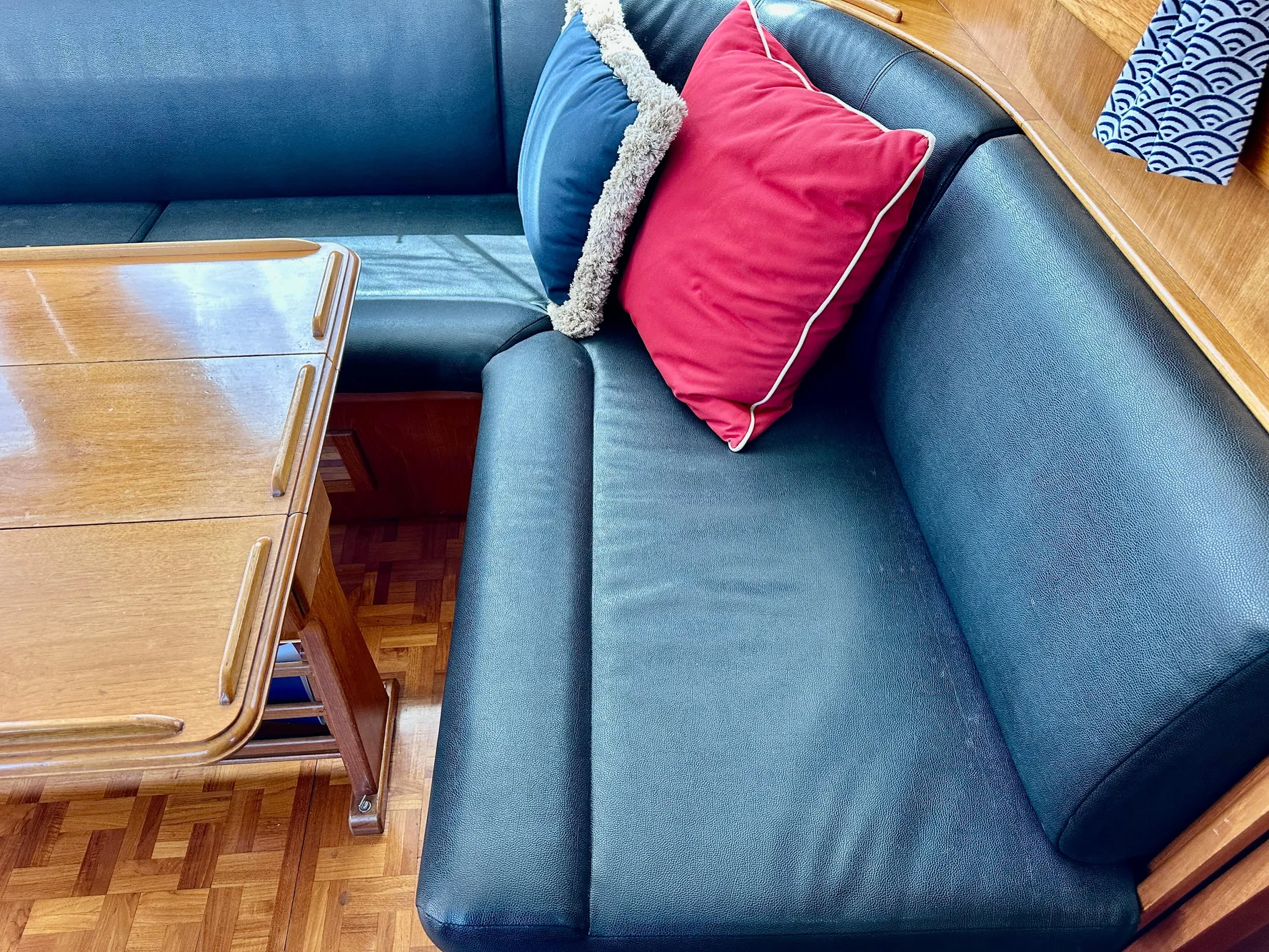 Grand Banks 42 Classic 1989 interior with blue seating, red cushion, and wooden table.