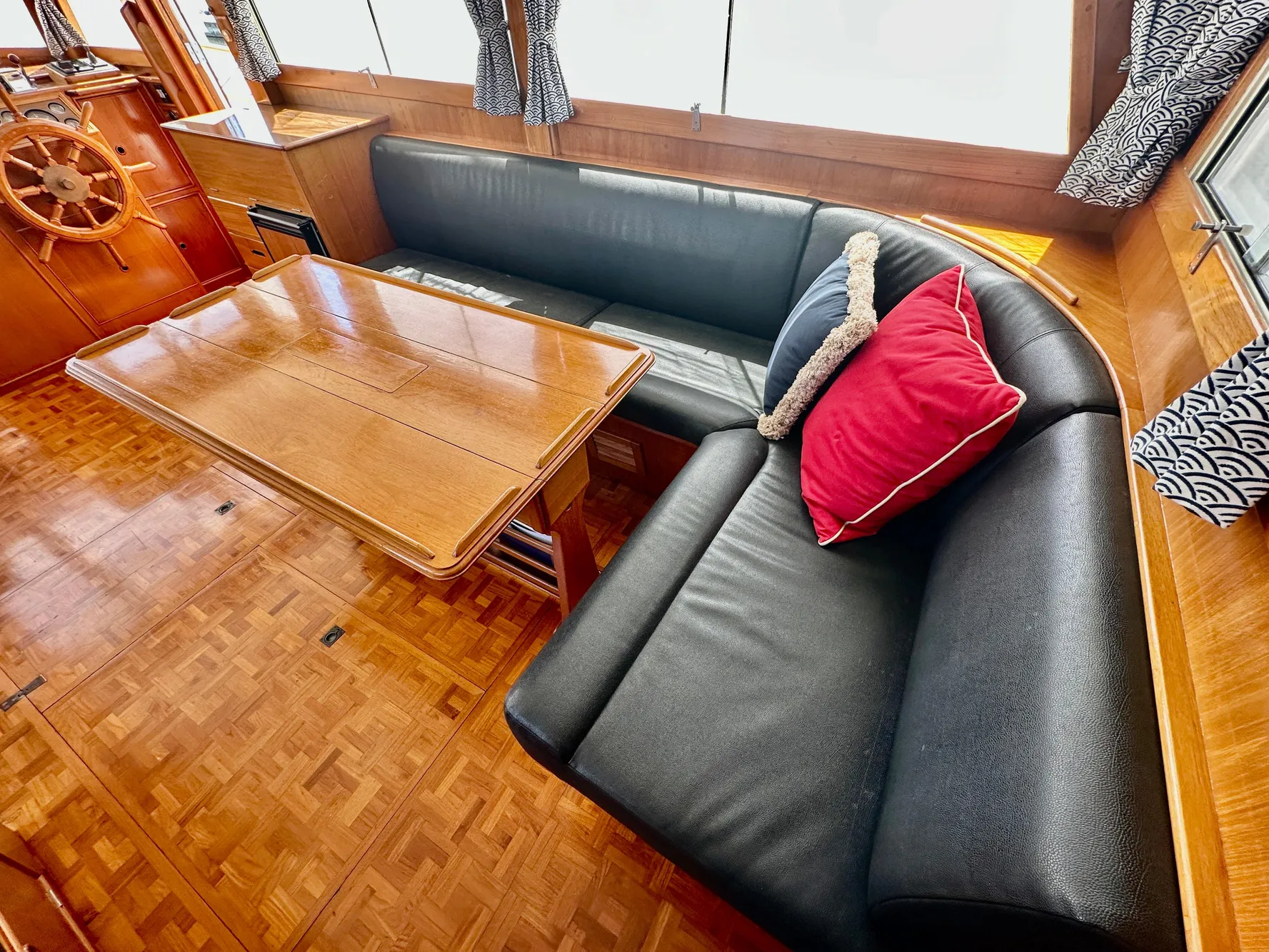 Interior of 1989 Grand Banks 42 Classic with wooden table and black leather seating.