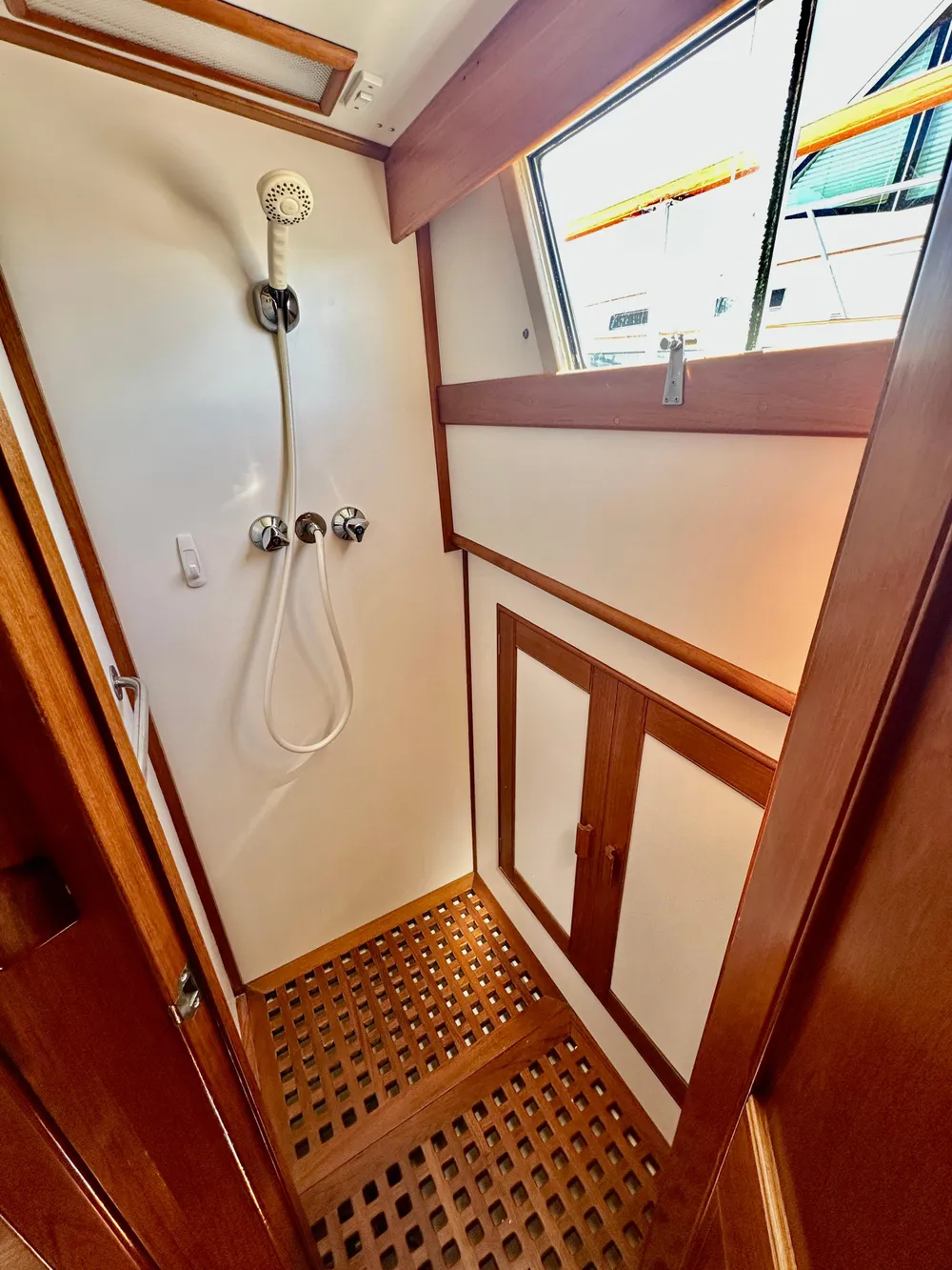 Shower area in 1989 Grand Banks 42 Classic yacht with wooden accents and window.