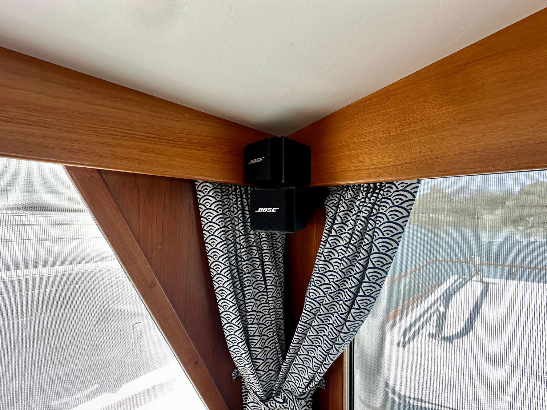 Bose speakers mounted in a 1989 Grand Banks 42 Classic yacht interior with patterned curtains.