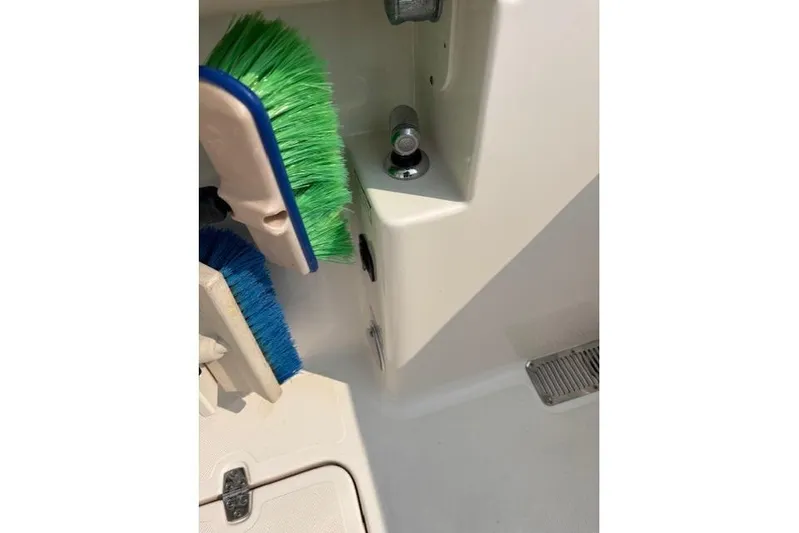 Syd Fishes Yacht Photos Pics 2017 Pursuit OS 325 Offshore boat interior with cleaning brushes and storage compartment.