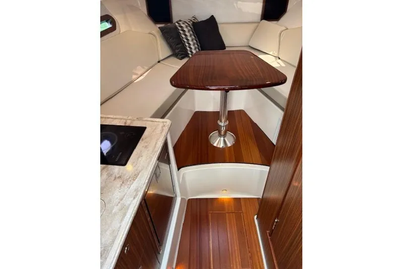 Syd Fishes Yacht Photos Pics 2017 Pursuit OS 325 Offshore cabin interior with wood flooring and table.