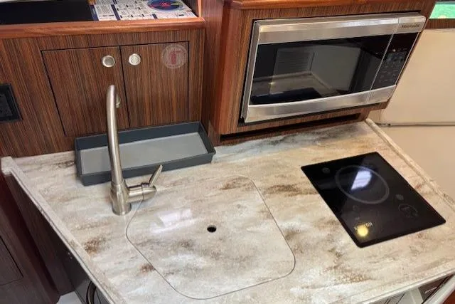 Syd Fishes Yacht Photos Pics Kitchen area of 2017 Pursuit OS 325 Offshore with sink, stove, and microwave.