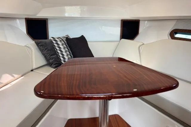 Syd Fishes Yacht Photos Pics 2017 Pursuit OS 325 Offshore cabin with wooden table and cushioned seating.