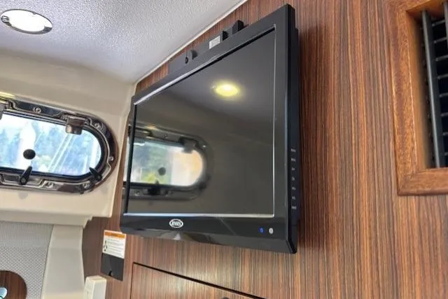 Syd Fishes Yacht Photos Pics Wall-mounted TV inside 2017 Pursuit OS 325 Offshore boat cabin with wood paneling.