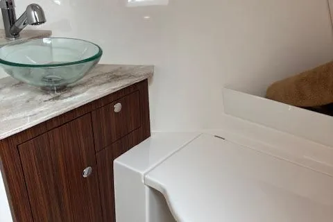 Syd Fishes Yacht Photos Pics 2017 Pursuit OS 325 Offshore bathroom with glass sink and wooden cabinet.