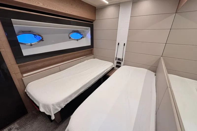  Yacht Photos Pics Interior of 2019 Pershing 70 yacht with twin beds and porthole windows.