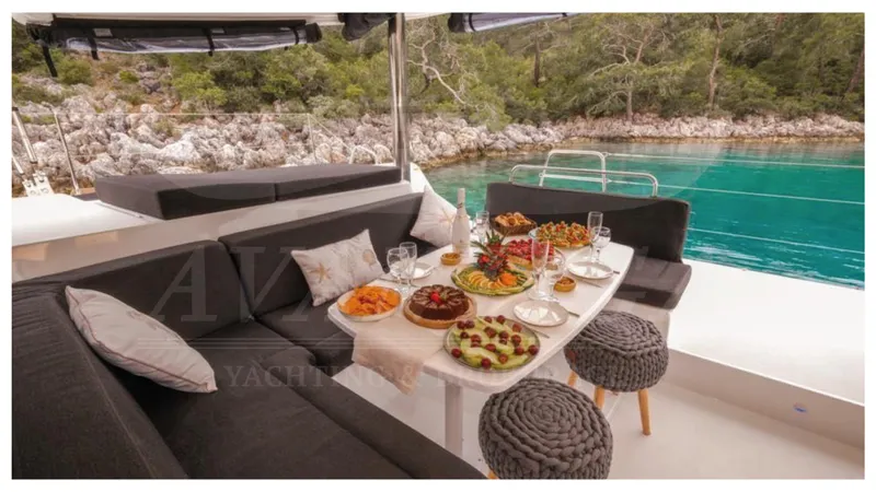  Yacht Photos Pics Luxurious Lagoon 52 F yacht with elegant dining setup, surrounded by serene turquoise waters and lush greenery.