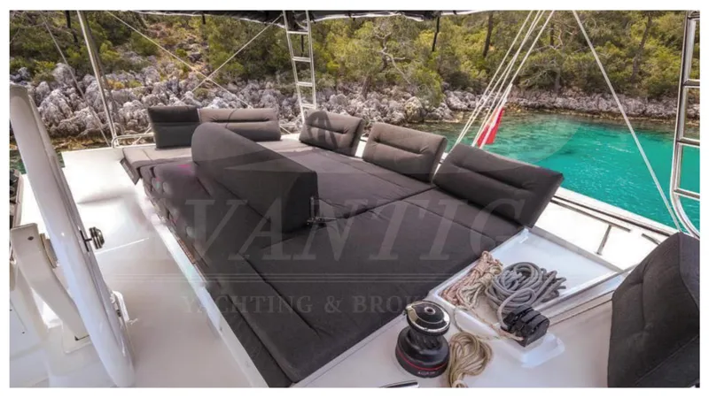  Yacht Photos Pics Luxurious Lagoon 52 F yacht deck with seating, ropes, and scenic turquoise water backdrop.