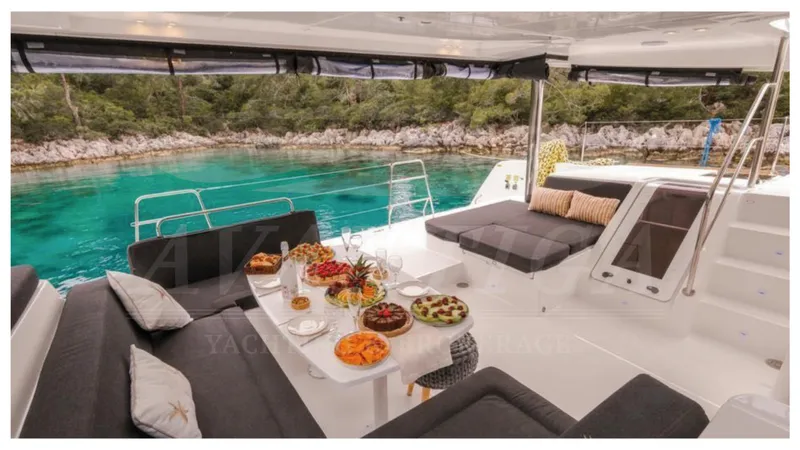  Yacht Photos Pics Luxurious Lagoon 52 F yacht interior with elegant seating and dining setup, overlooking serene turquoise waters.