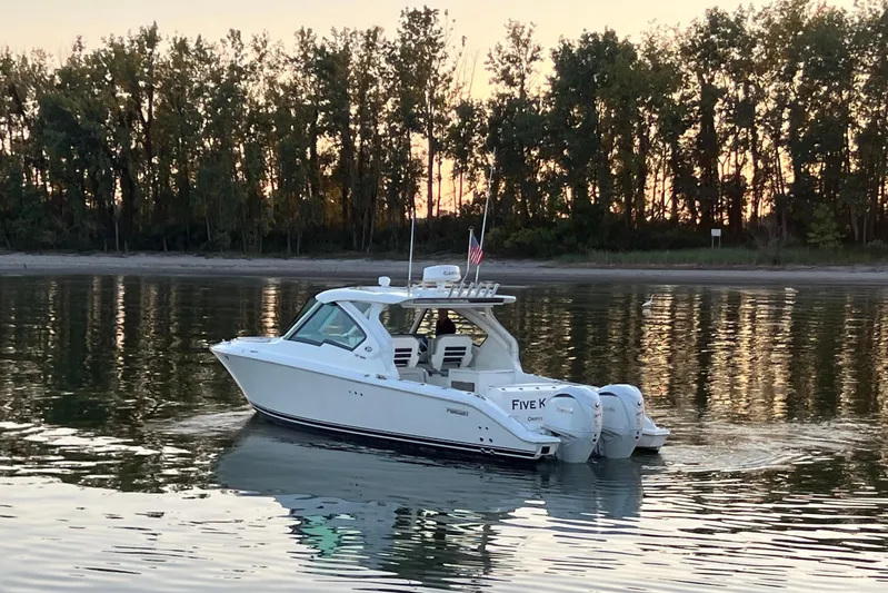  Yacht Photos Pics 2023 Pursuit DC 326 Dual Console boat cruising on calm water at sunset.