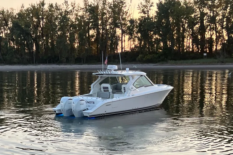  Yacht Photos Pics 2023 Pursuit DC 326 Dual Console boat on calm water at sunset.