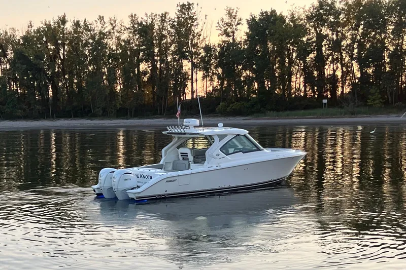  Yacht Photos Pics 2023 Pursuit DC 326 Dual Console boat on calm water at sunset.