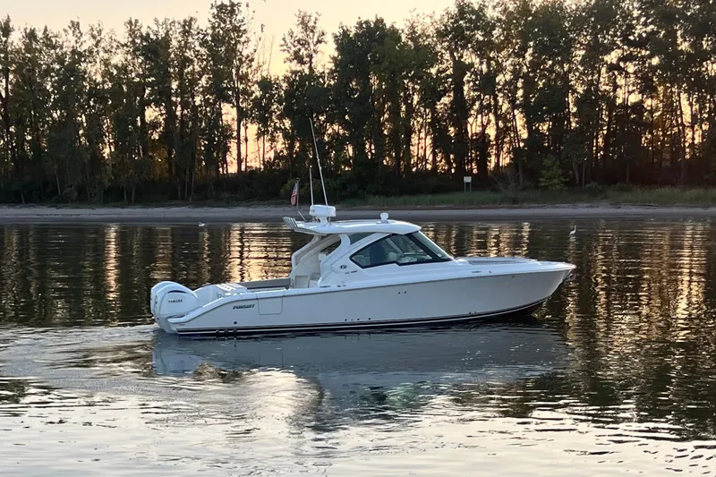  Yacht Photos Pics 2023 Pursuit DC 326 Dual Console boat cruising on calm water at sunset.