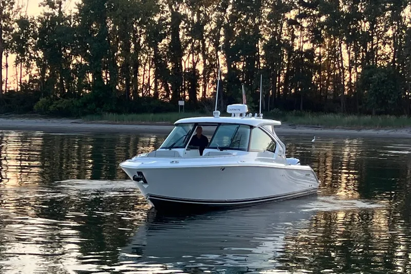  Yacht Photos Pics 2023 Pursuit DC 326 Dual Console boat on calm water at sunset.