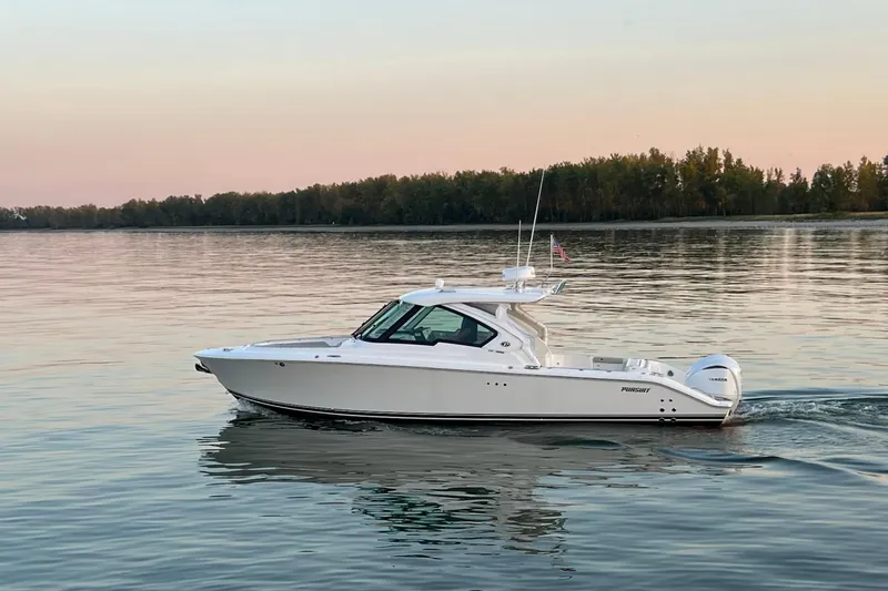  Yacht Photos Pics 2023 Pursuit DC 326 Dual Console boat cruising on calm water at sunset.