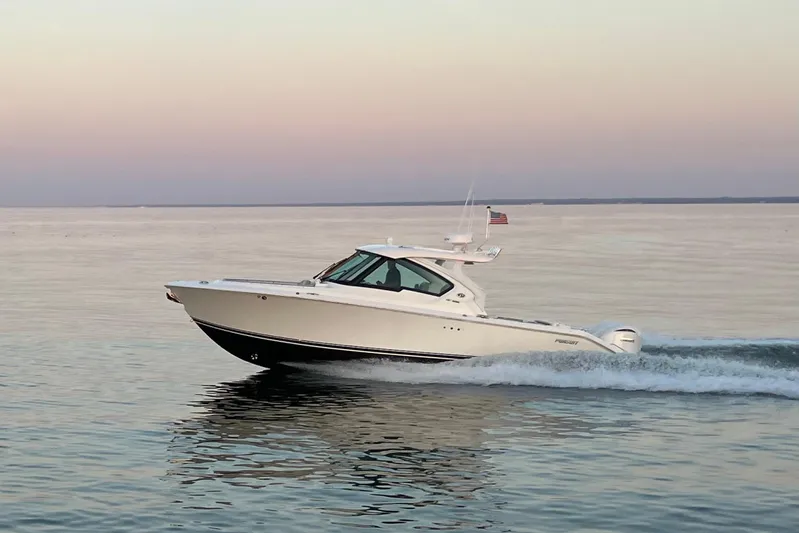  Yacht Photos Pics 2023 Pursuit DC 326 Dual Console boat cruising on calm water at sunset.