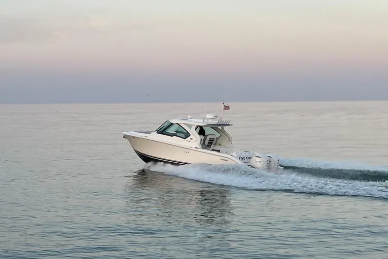 Yacht Photos Pics 2023 Pursuit DC 326 Dual Console cruising on calm waters at sunset.
