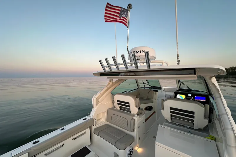  Yacht Photos Pics 2023 Pursuit DC 326 Dual Console boat on calm water at sunset with American flag.